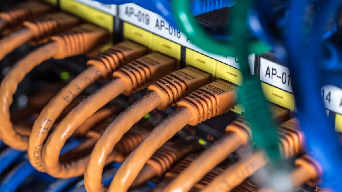 Orange Ethernet cables connected to a row of yellow network ports.