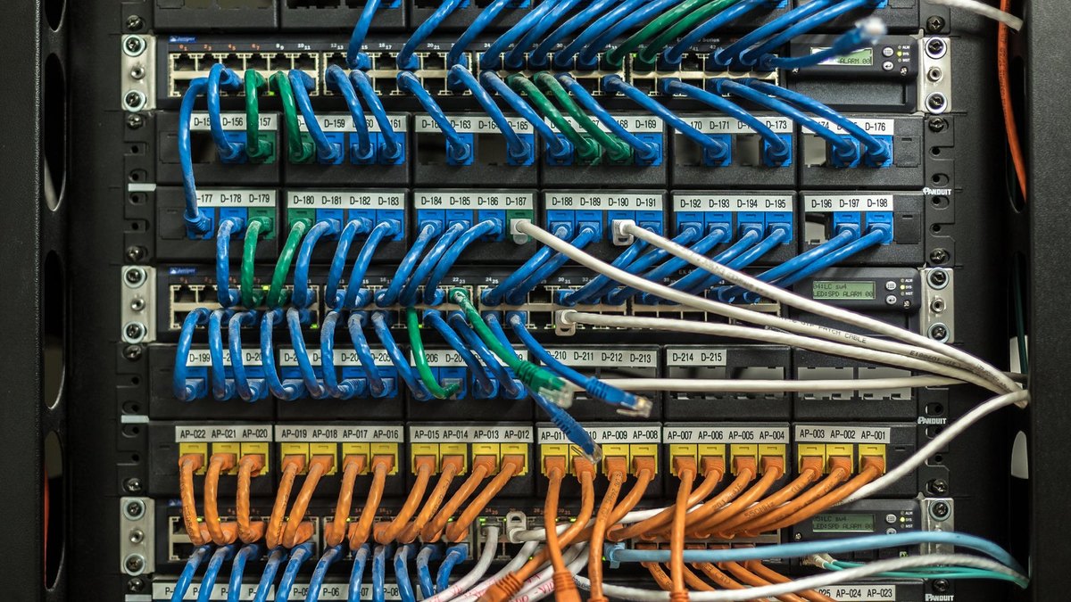 Blue, orange and white cables linking equipment in a network rack.