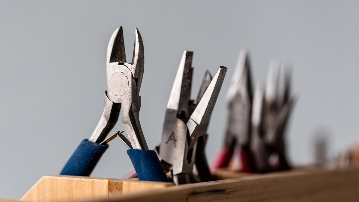 Several pairs of pliers and cutters stored upright in a wooden holder.