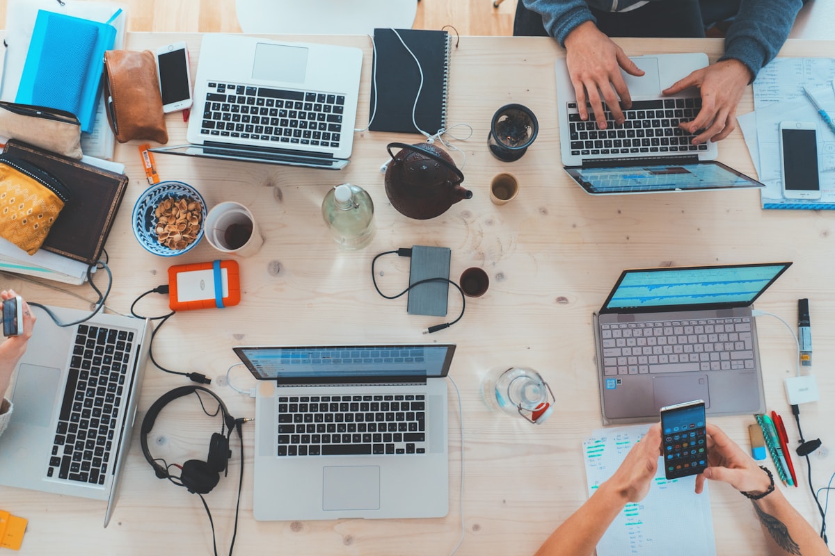 An overhead view of people working with laptops and notes around a shared table.